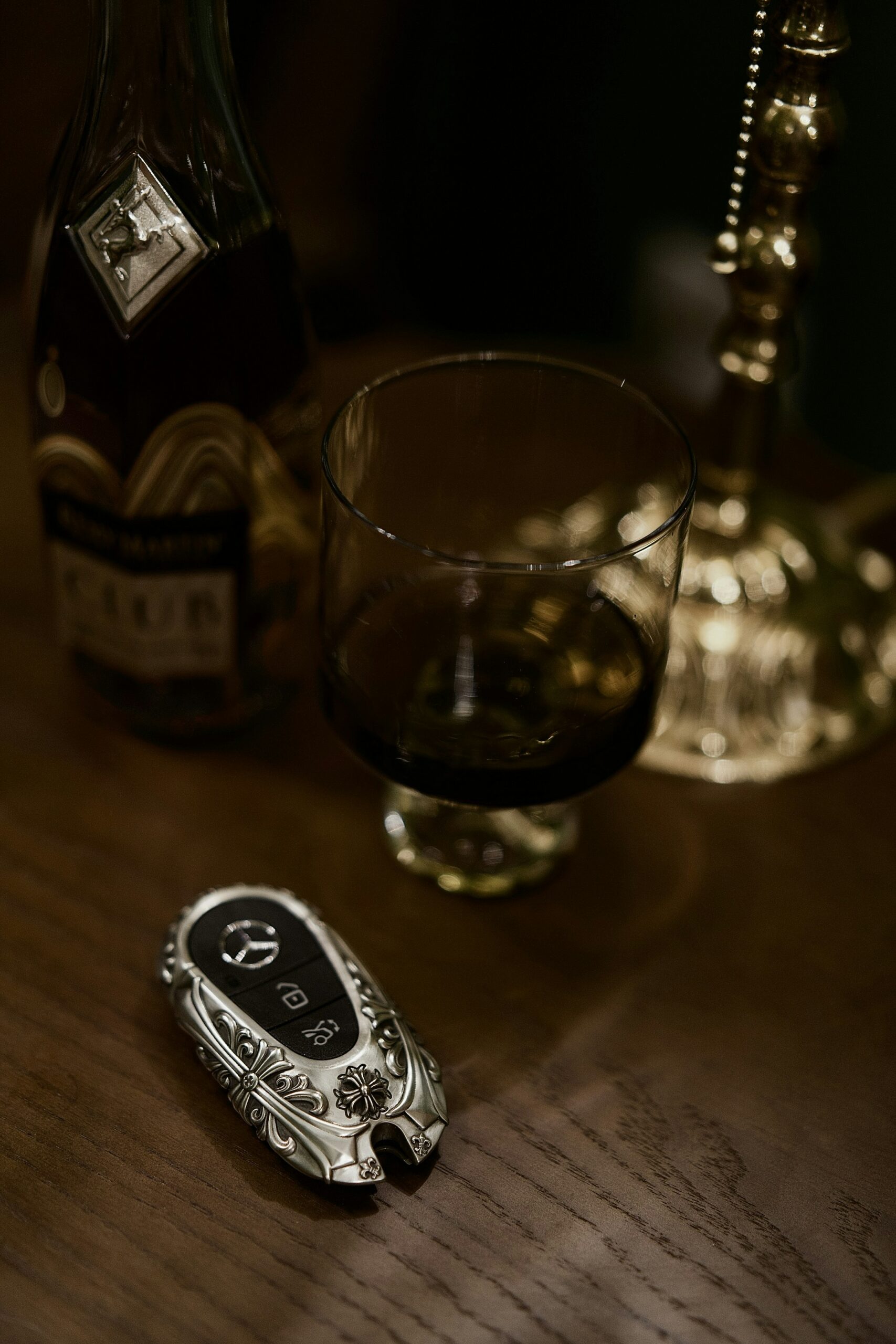 Autoschlüssel neben einer Flasche und einem Glas auf einem Tisch