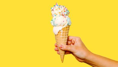 Hand hält eine Eiswaffel mit Streuseln – Symbolbild für Eisdielen und Eiscafés