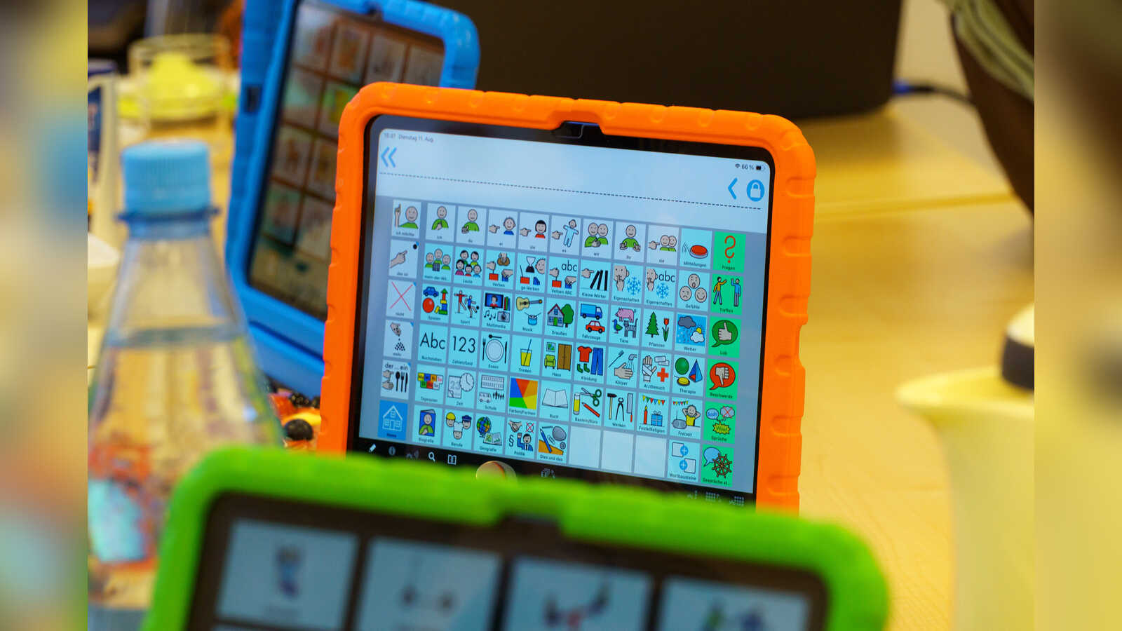 Tablet in orangefarbener Schutzhülle zeigt ein Symbolraster einer Kommunikations-App