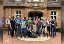 Gruppe von Männern mit Wanderstöcken vor dem Marstall Clemenswerth in Sögel