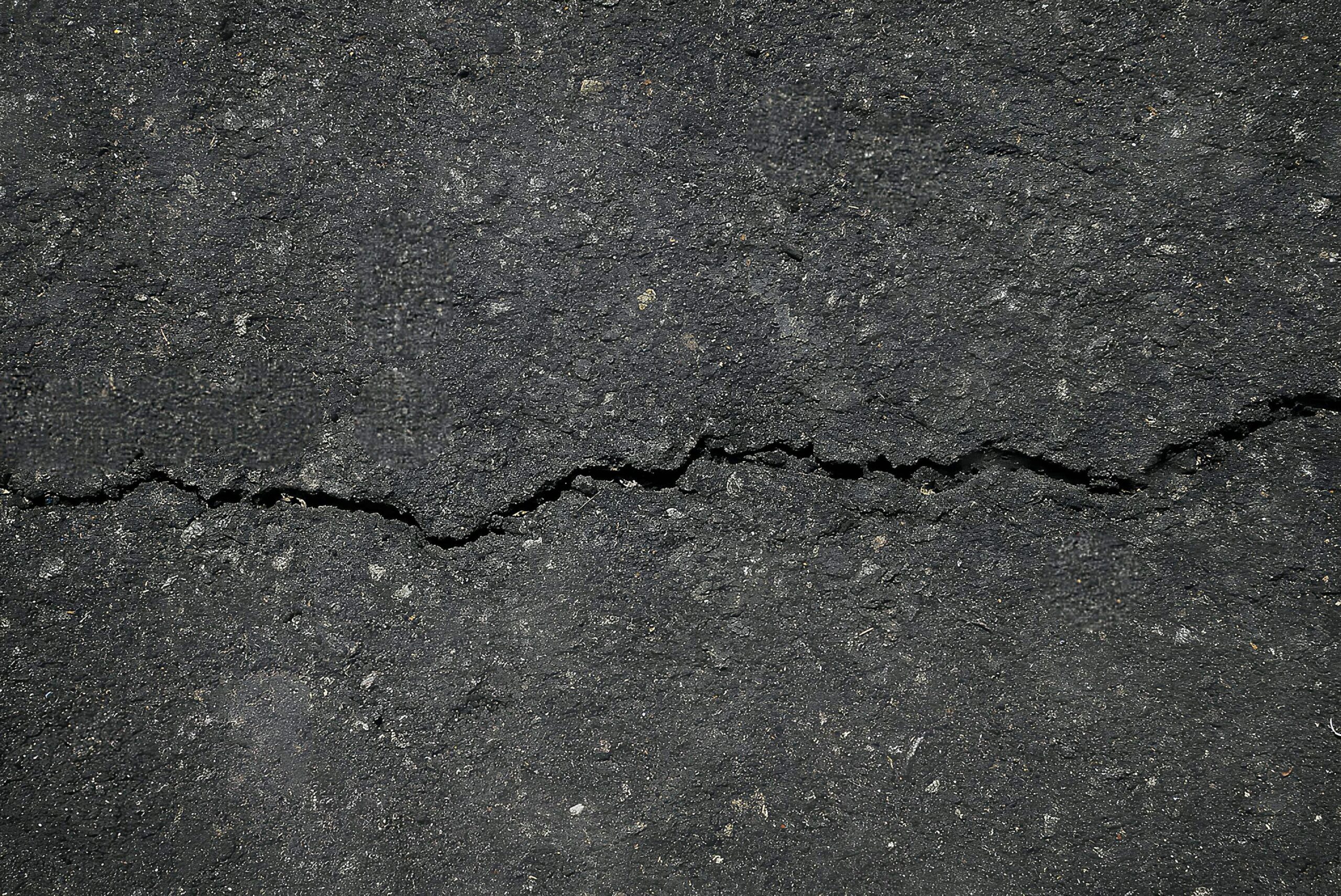Rissiger Asphalt auf einer Straße, Symbolbild für Fahrbahnschäden