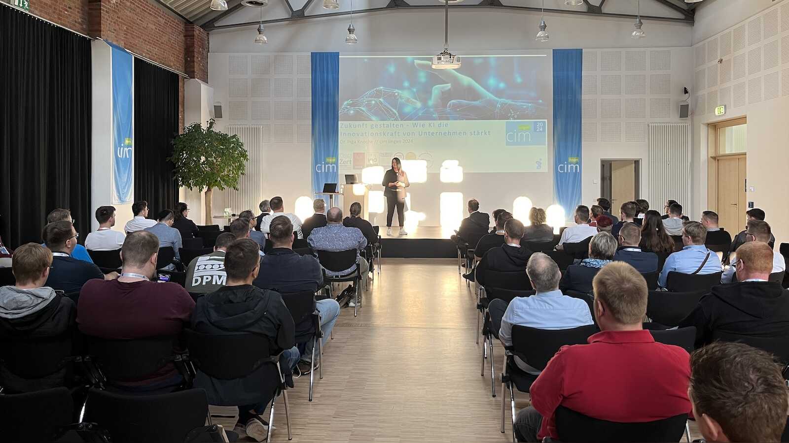 Blick durch den Saal des IT-Zentrums Lingen auf eine Rednerin und die Leinwand mit einem Vortrag über Künstliche Intelligenz