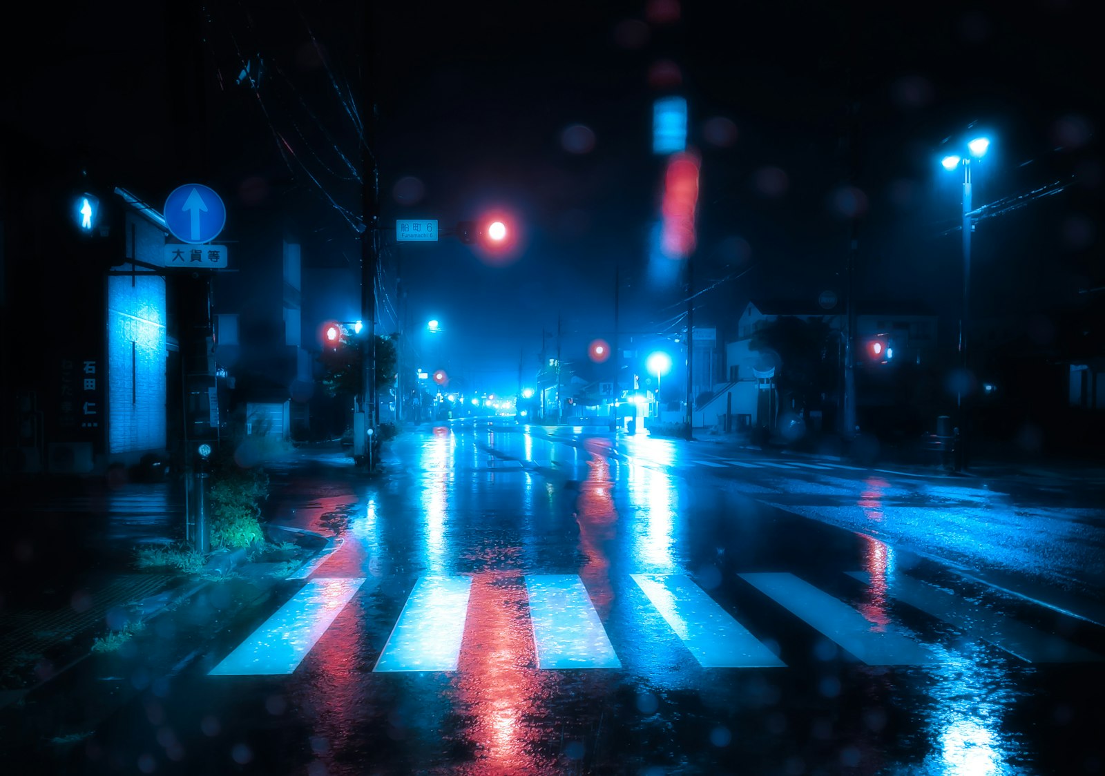 Nasser Fußgängerüberweg bei Nacht mit gespiegelten Ampellichtern