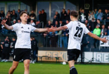 Zwei Fußballer des SC Spelle-Venhaus im weißen Trikot klatschen sich nach einem Tor ab