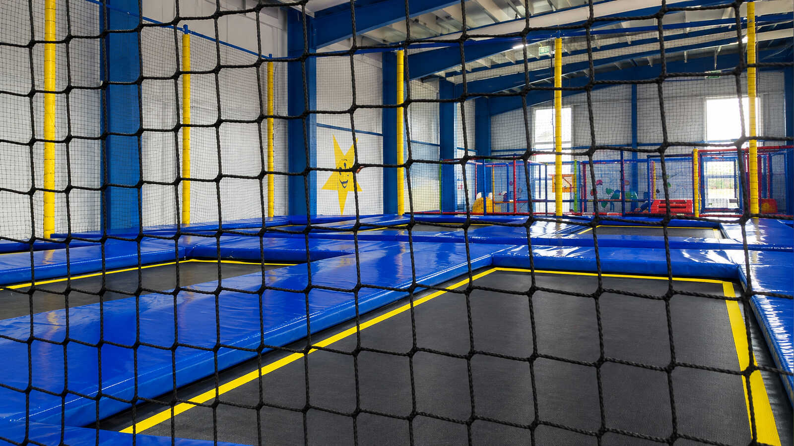 Mehrere in den Boden eingelassene Trampoline hinter einem Sicherheitsnetz