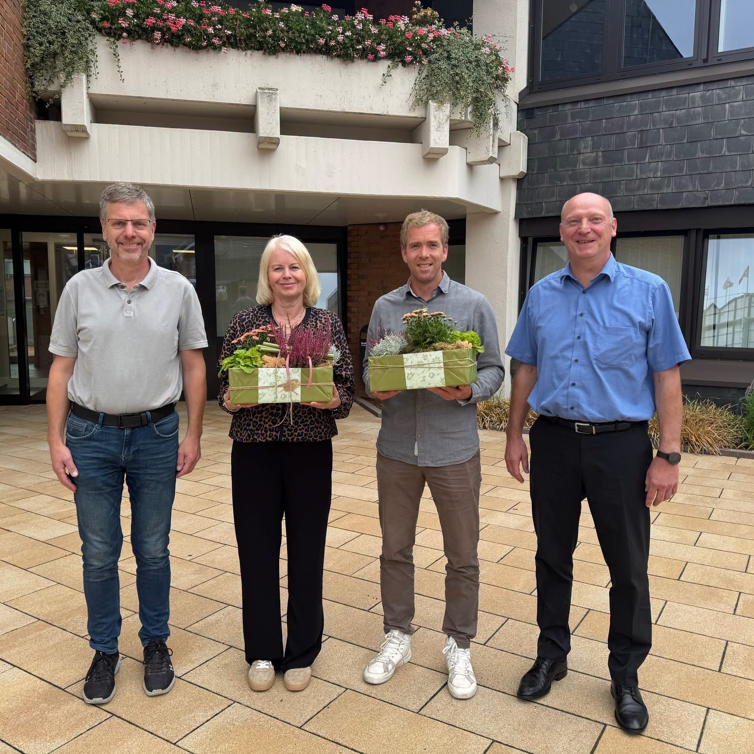 Godehard Ritz, Brigitte Bekel, Philipp Mey und Mathias Brinker stehen mit Blumengeschenken vor dem Rathaus der Samtgemeinde Freren