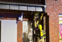 Feuerwehrleute mit Atemschutz auf einer Steigleiter bei der Kontrolle des Gebäudes am Verbrauchermarkt in Schüttorf