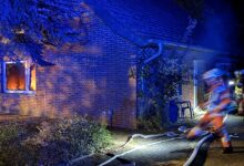 Feuerwehrfahrzeuge mit Blaulicht auf einer Straße in Werlte während des Löscheinsatzes bei Nacht