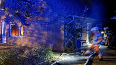 Feuerwehrfahrzeuge mit Blaulicht auf einer Straße in Werlte während des Löscheinsatzes bei Nacht