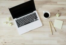 Notizbuch, Laptop und Kaffee auf einem Schreibtisch