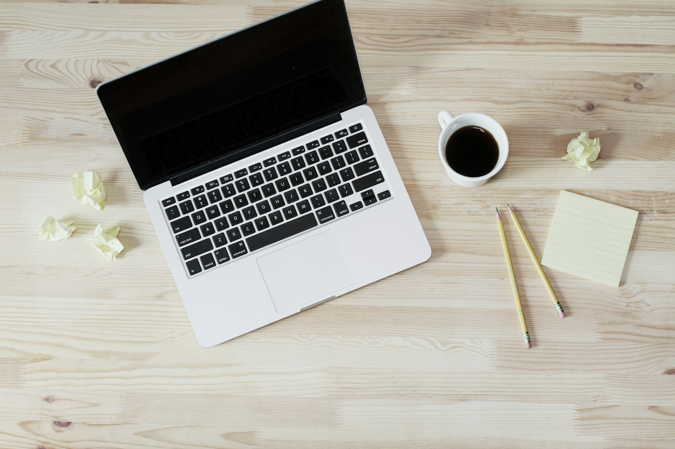 Notizbuch, Laptop und Kaffee auf einem Schreibtisch