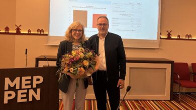 Dr. Sigrid Kraujuttis mit Blumenstrauß neben einem Gratulanten im Ratssaal Meppen, im Hintergrund die Präsentation der Wahlergebnisse