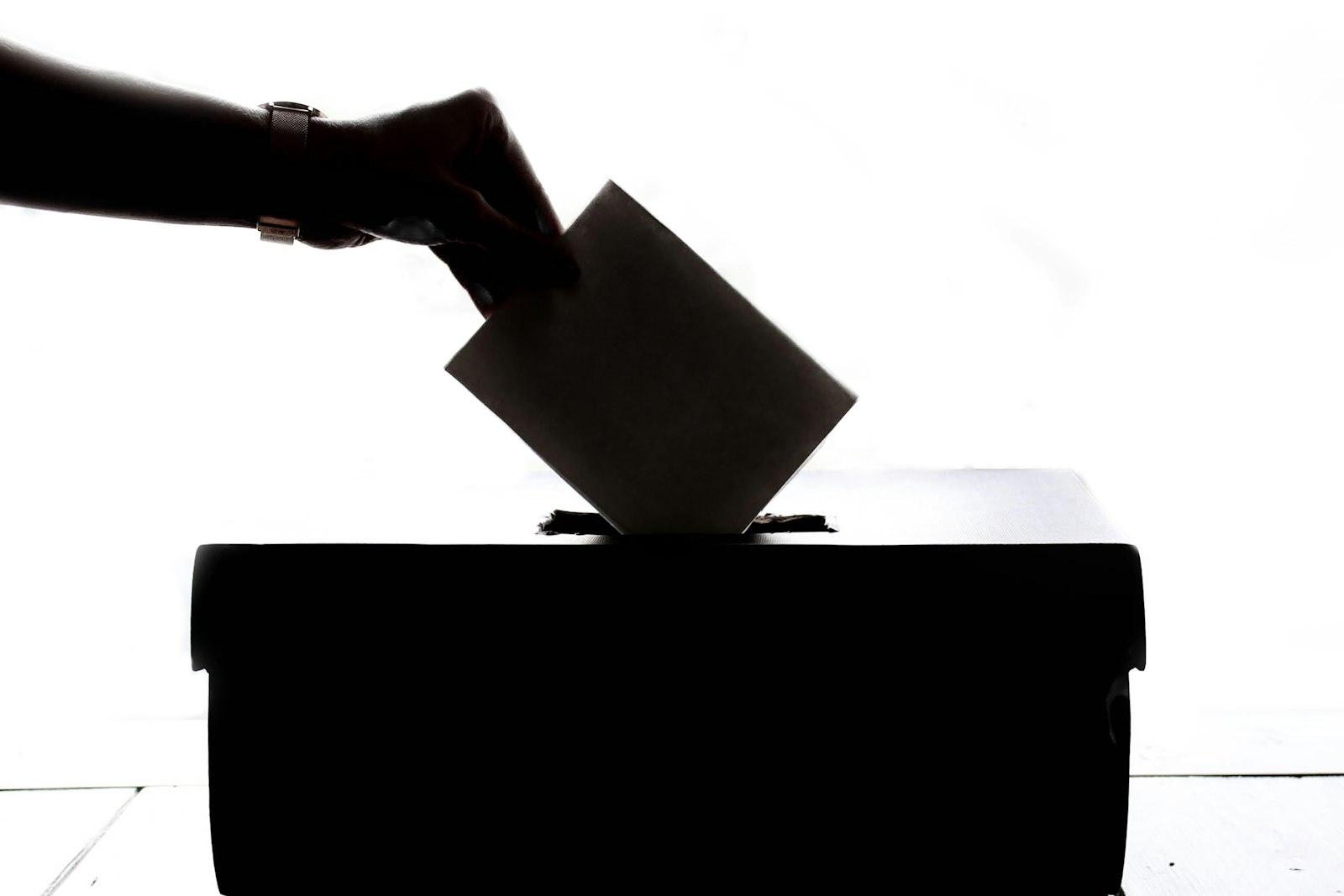 Eine Person wirft einen Stimmzettel in eine Wahlurne