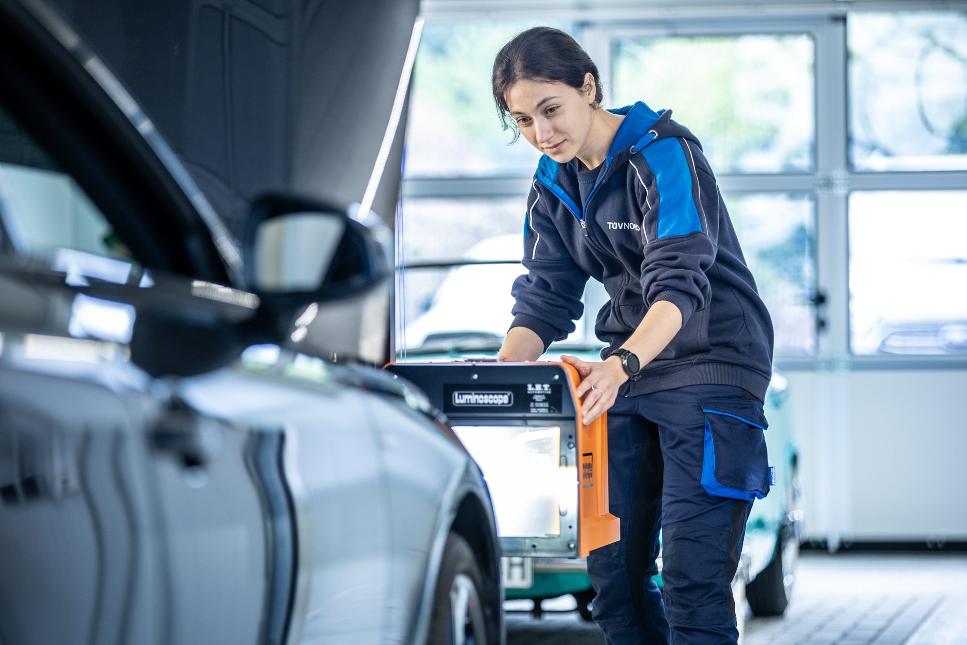 Prüferin von TÜV NORD führt einen Lichtcheck an einem Fahrzeug durch