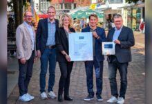 IHK-Hauptgeschäftsführer Marco Graf und Bürgermeister Thomas Berling präsentieren gemeinsam mit weiteren Beteiligten die Auszeichnungsurkunde für Nordhorn