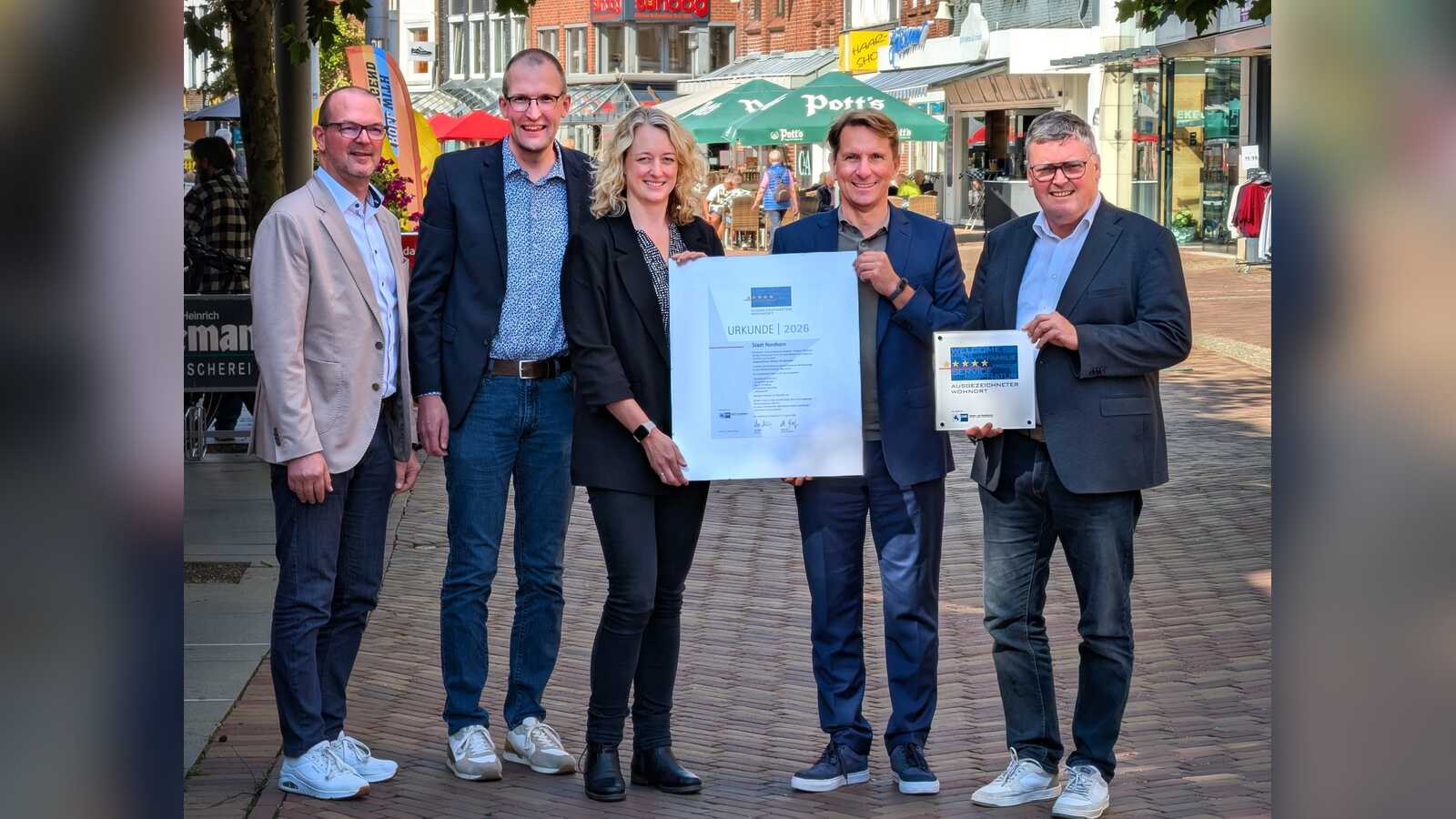 IHK-Hauptgeschäftsführer Marco Graf und Bürgermeister Thomas Berling präsentieren gemeinsam mit weiteren Beteiligten die Auszeichnungsurkunde für Nordhorn