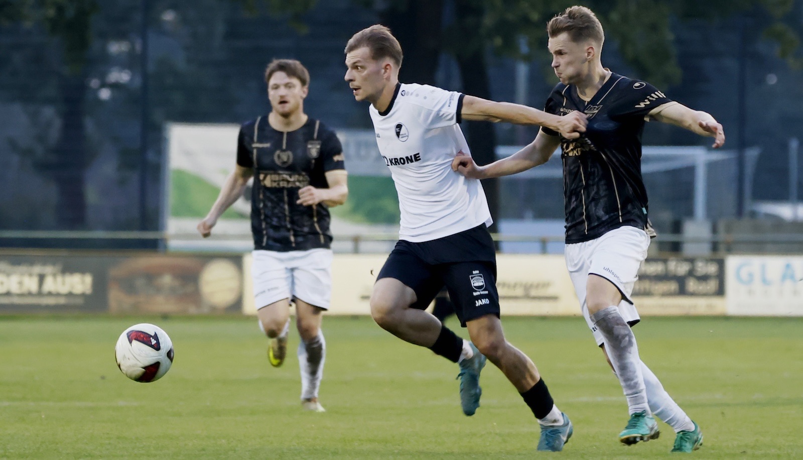 Adrian Lenz vom SC Spelle-Venhaus im weißen Trikot im Zweikampf mit einem Gegenspieler in Schwarz
