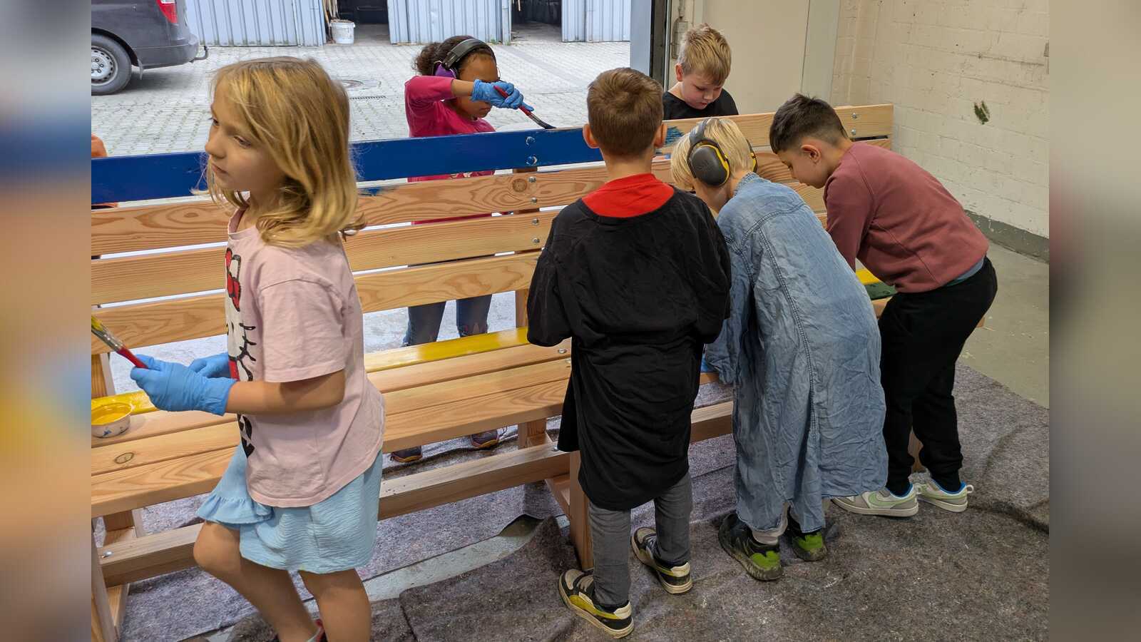 Schülerinnen und Schüler der Pestalozzischule Meppen bemalen eine Holzbank in der VHS Jugendwerkstatt