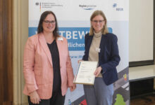 Melanie Schade vom BBSR überreicht Nordhorns Stadtbaurätin Milena Schauer die Siegerurkunde