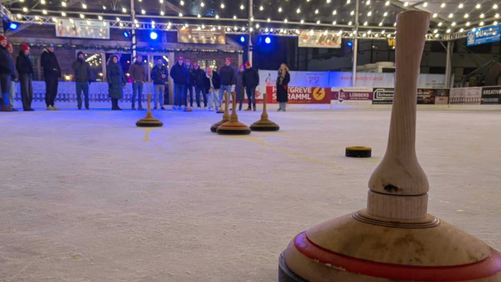 Eisstock im Vordergrund auf der überdachten Eisbahn des Lingener Weihnachtsmarktes