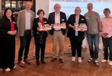 Sieben Personen stehen vor einer Leinwand mit dem Titel des Fachtags Innovatives Wohnen