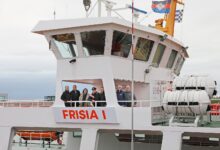 Sieben Personen stehen auf der Brückennock der weißen Inselfähre Frisia I