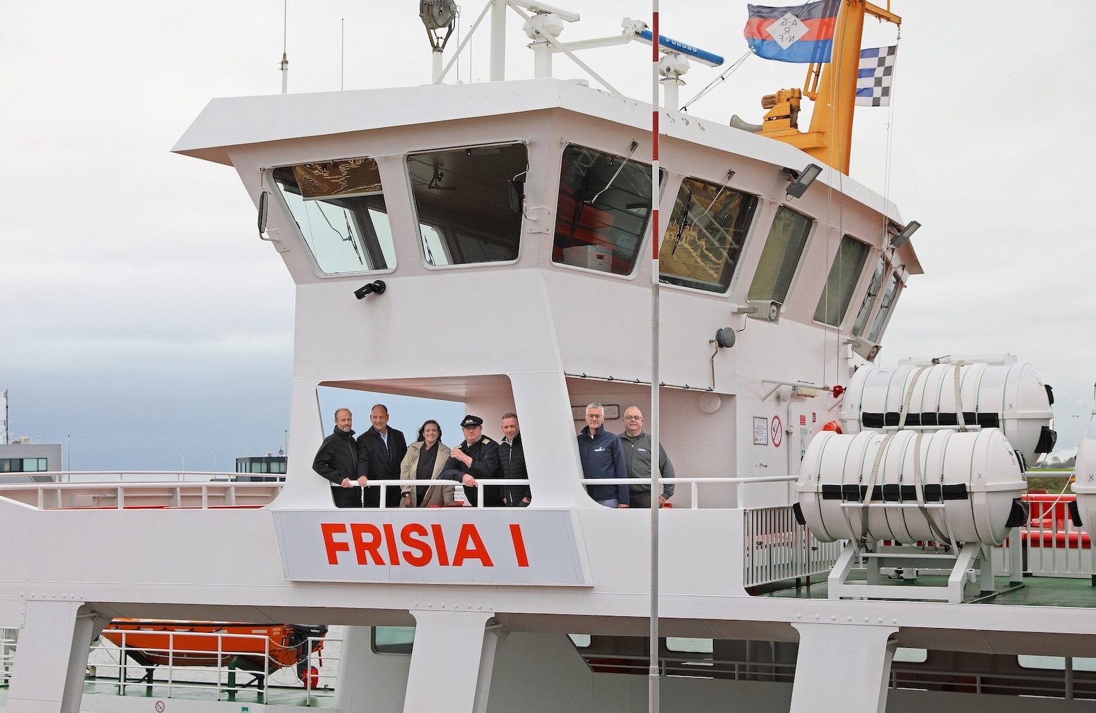 Sieben Personen stehen auf der Brückennock der weißen Inselfähre Frisia I