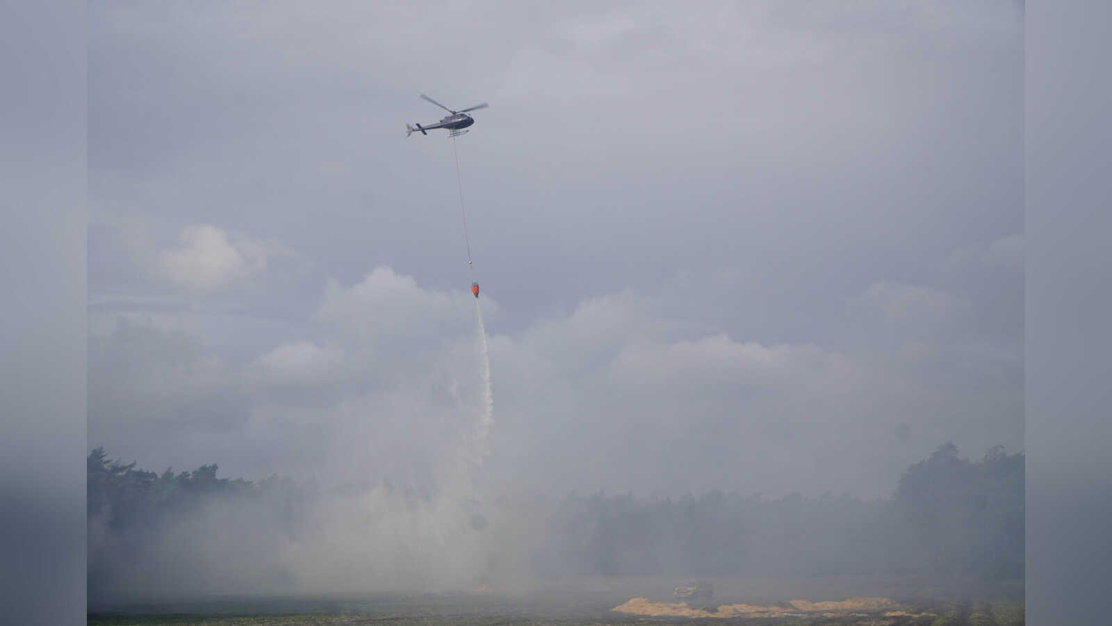 Hubschrauber wirft bei der Übung in Itterbeck Löschwasser über einem simulierten Vegetationsbrand ab