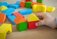 Kinderhand stapelt bunte Holzbausteine