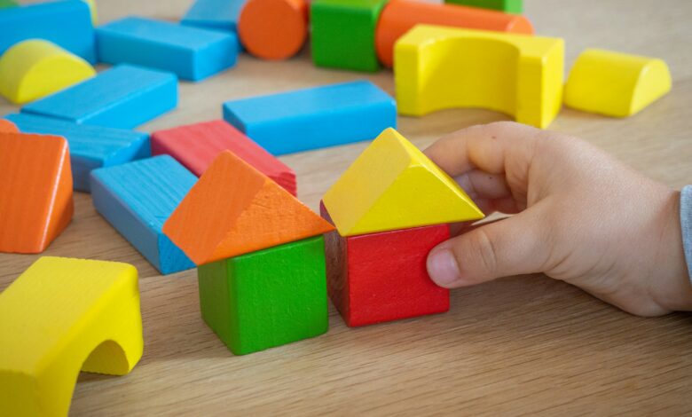 Kinderhand stapelt bunte Holzbausteine
