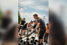 Ehrenamtliche tragen beim Aufbau des LAUTFEUER Festivals Metallteile für die Bühne