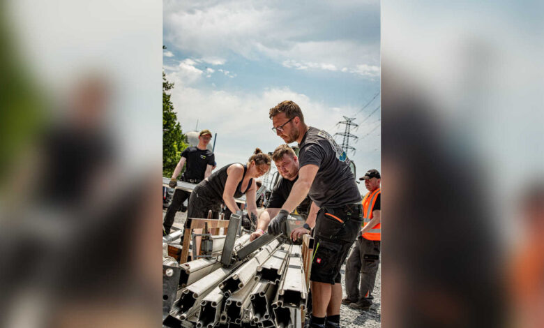 Ehrenamtliche tragen beim Aufbau des LAUTFEUER Festivals Metallteile für die Bühne