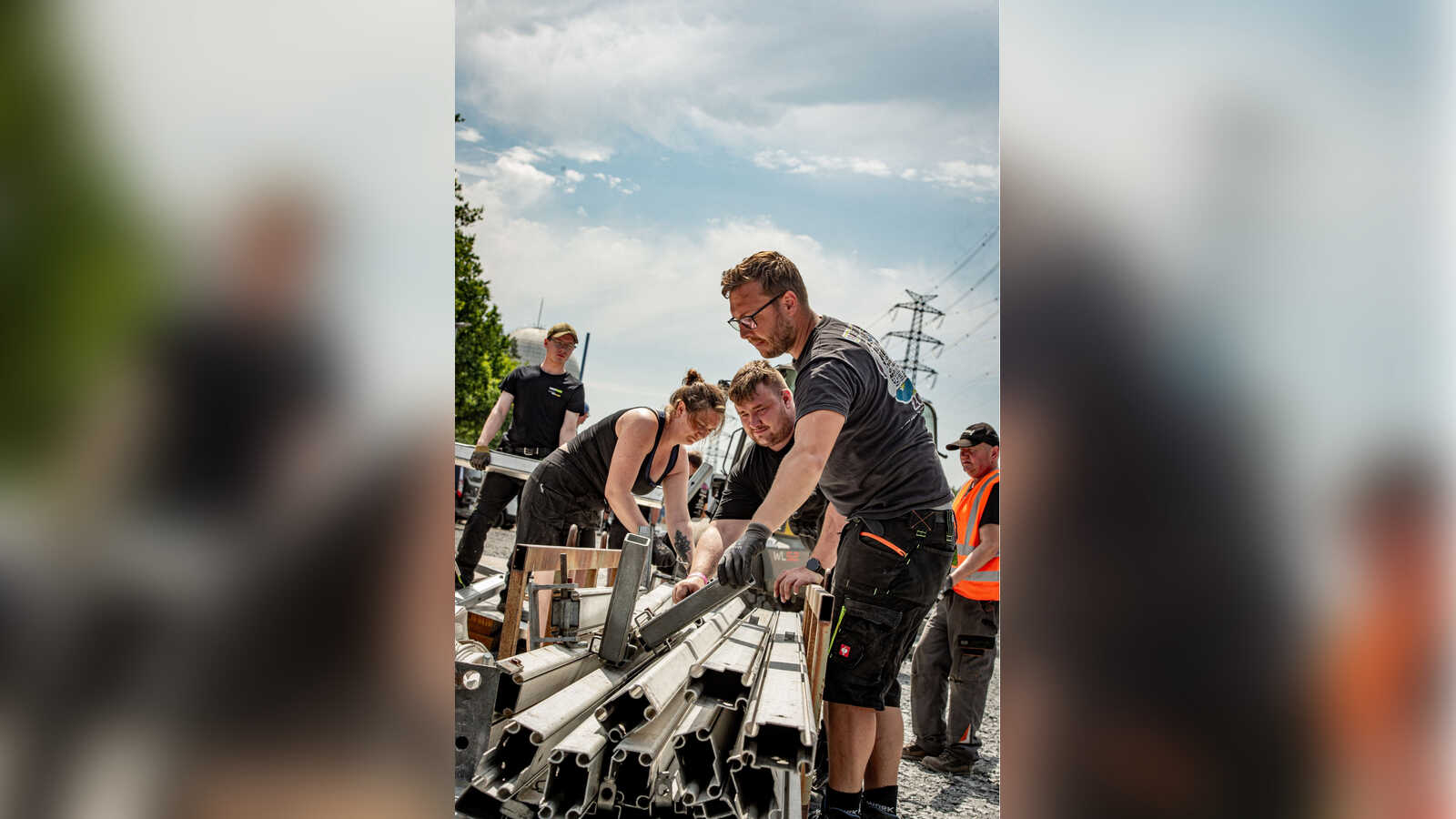 Ehrenamtliche tragen beim Aufbau des LAUTFEUER Festivals Metallteile für die Bühne