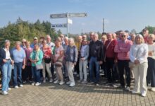 Gruppenfoto der Lingener Reisegruppe im Freien an einem Wegweiser mit Richtungsschildern nach Lingen und Hronov