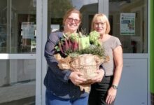 Zwei Frauen vor dem Eingang der Kita Zwergenglück in Surwold, eine hält einen großen Blumentopf mit Heide und Hortensien