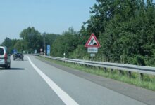 Baustellen-Warnschild an einer Straße mit Leitplanke