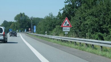 Baustellen-Warnschild an einer Straße mit Leitplanke