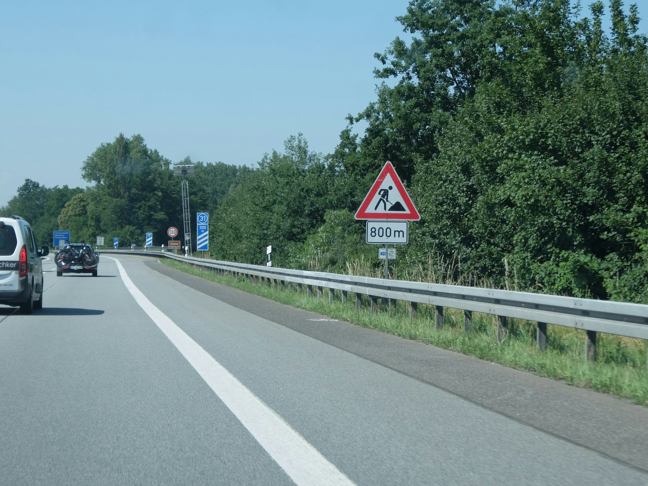 Baustellen-Warnschild an einer Straße mit Leitplanke