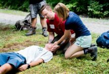 Ein Ersthelfer übt im Freien die Herzdruckmassage an einer liegenden Person