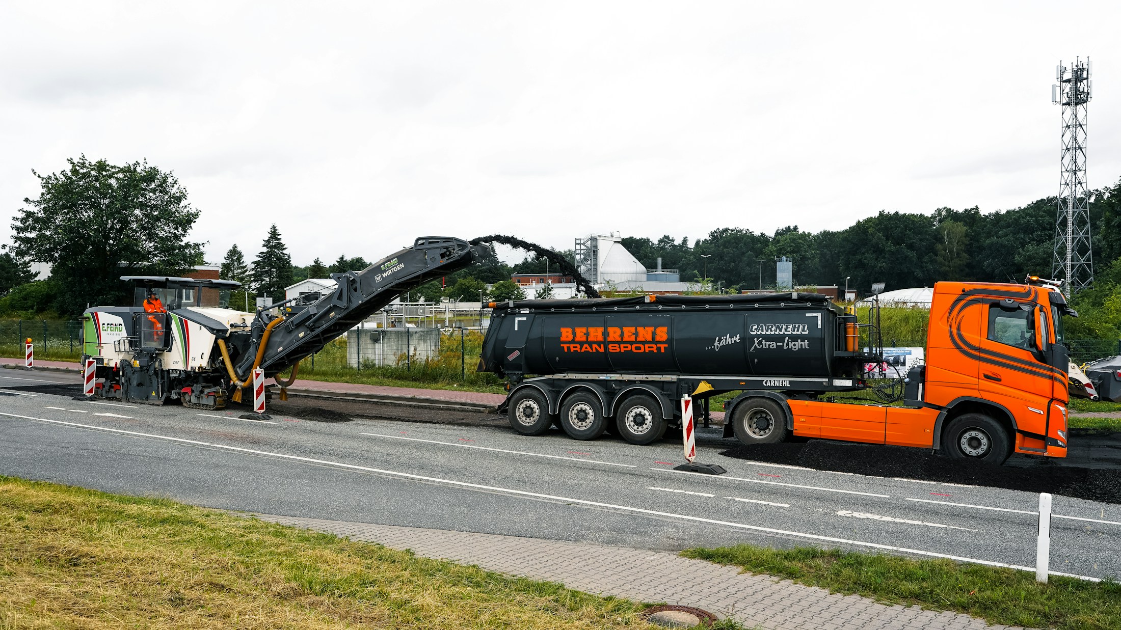 Eine Straßenfräse trägt die alte Asphaltdecke ab und lädt sie auf einen Lkw