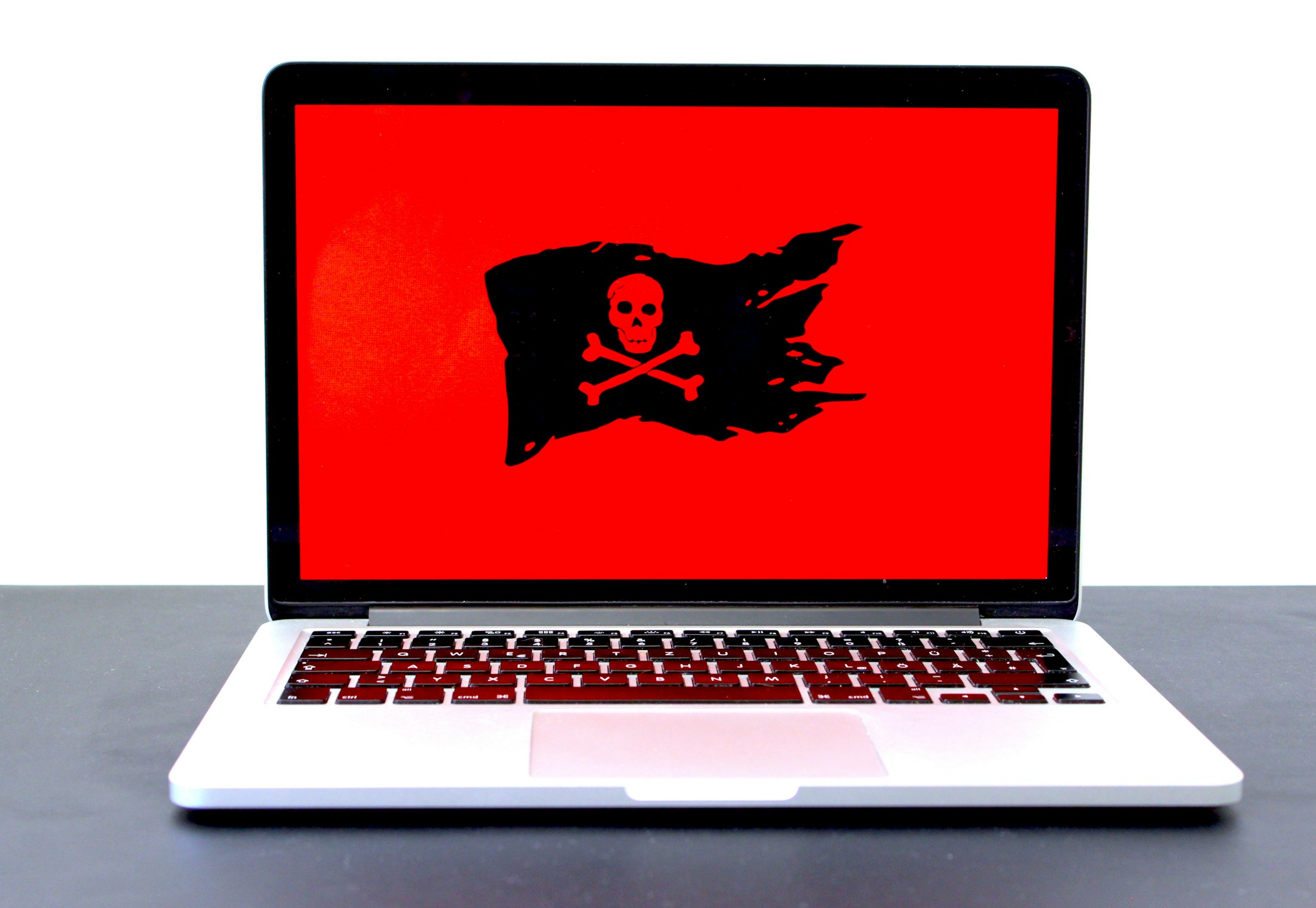 Laptop mit Totenkopf-Symbol auf rotem Bildschirm als Zeichen für einen Hackerangriff