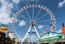 Riesenrad inmitten von Fahrgeschäften auf einem Rummelplatz