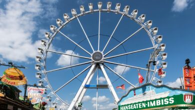 Riesenrad inmitten von Fahrgeschäften auf einem Rummelplatz