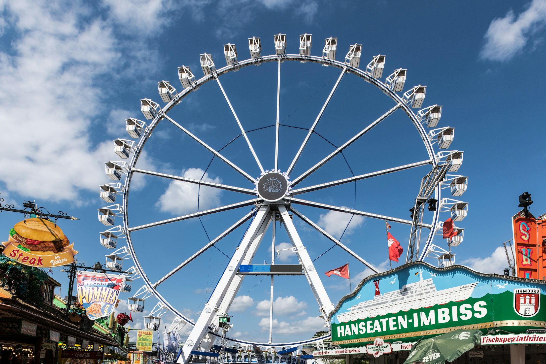 Riesenrad inmitten von Fahrgeschäften auf einem Rummelplatz
