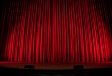 Publikum vor einer beleuchteten Theaterbühne