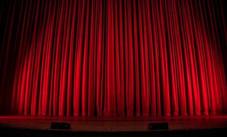 Publikum vor einer beleuchteten Theaterbühne