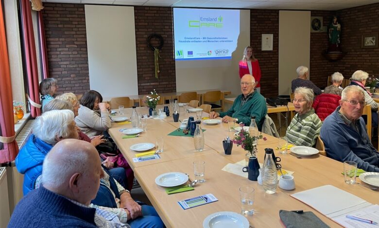 Seniorinnen und Senioren an langen Tischen, vorne steht Franziska Fehnker vor einer Leinwand mit dem EmslandCare-Logo