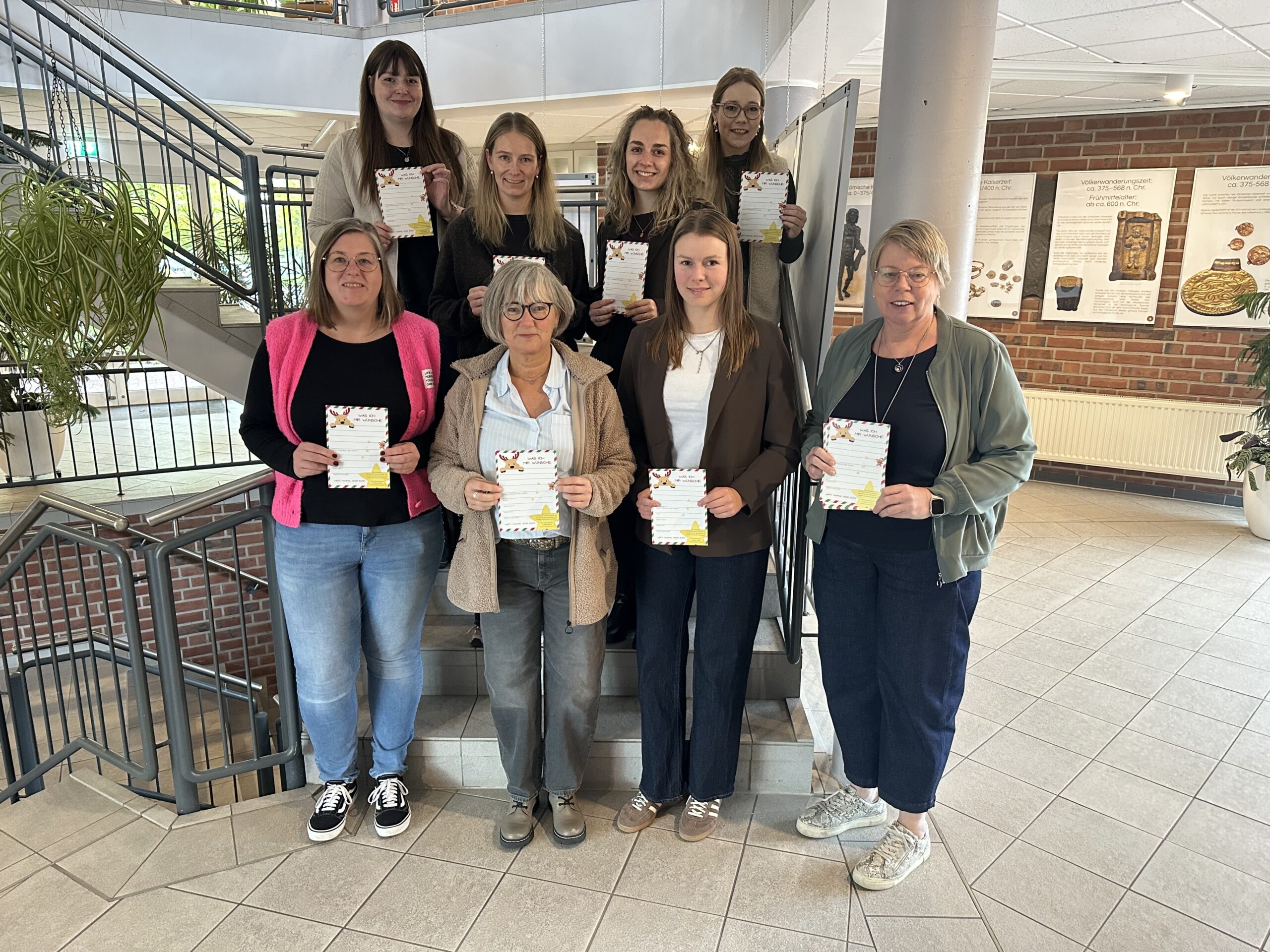 Acht Frauen stehen auf einer Treppe im Rathausfoyer und halten Wunschzettel in den Händen